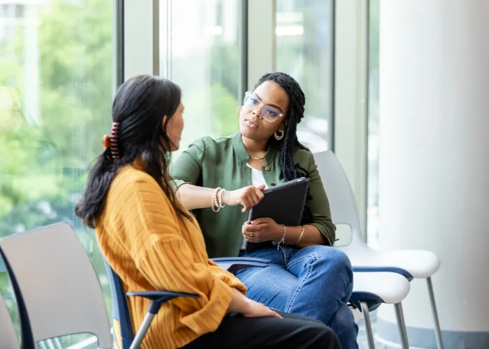 An empathetic female counselor listens as a vulnerable patient shares about a difficult situation.