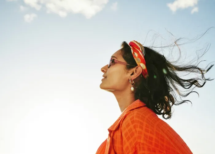 Side view of a young woman looking up at the sky and smiling during a sunny day in summer